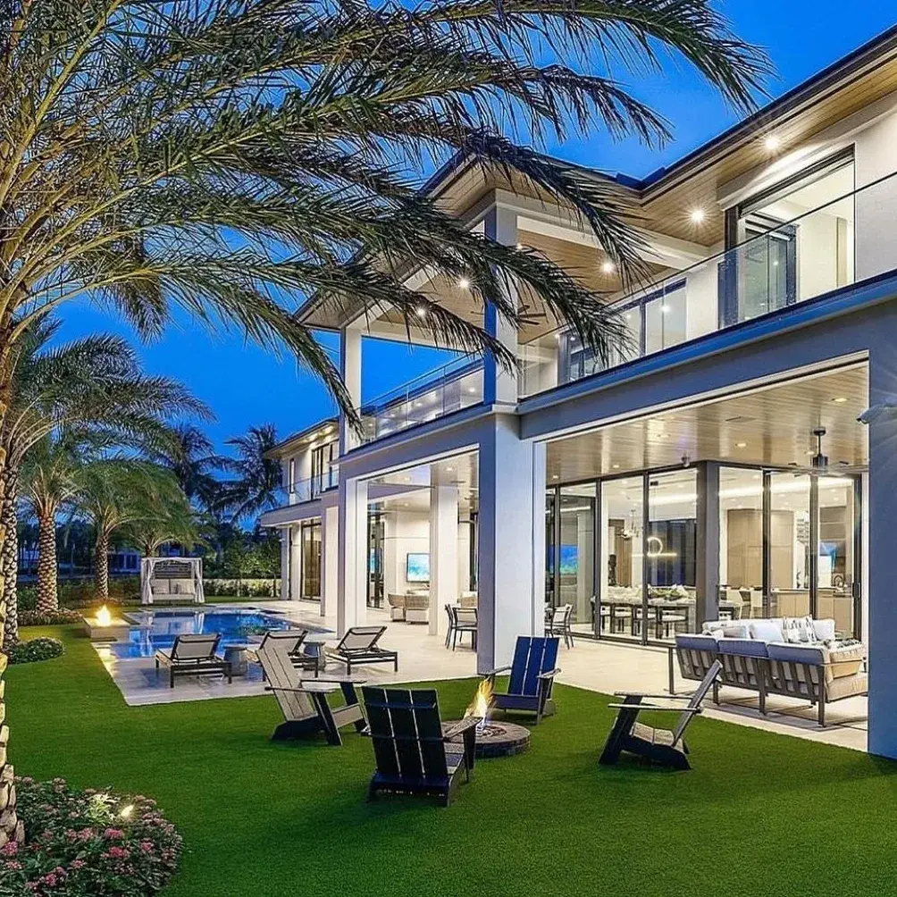 Fachada noturna da Casa Horizonte, com grandes panos de vidro, varandas, piscina e jardim tropical.