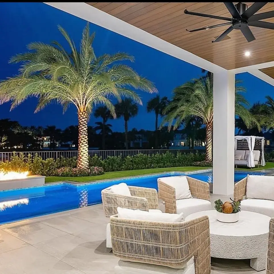 Varanda coberta da Casa Horizonte voltada para a piscina, com mobiliário em fibras naturais e jardim de palmeiras.