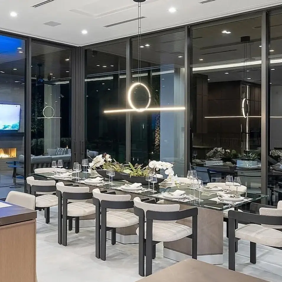 Sala de jantar da Casa Horizonte com mesa para dez lugares, luminária escultórica e fechamento integral em vidro.
